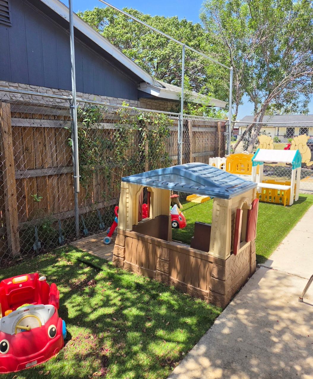 Playhouse next to the daycare building with a Texas Rising Star certification banner