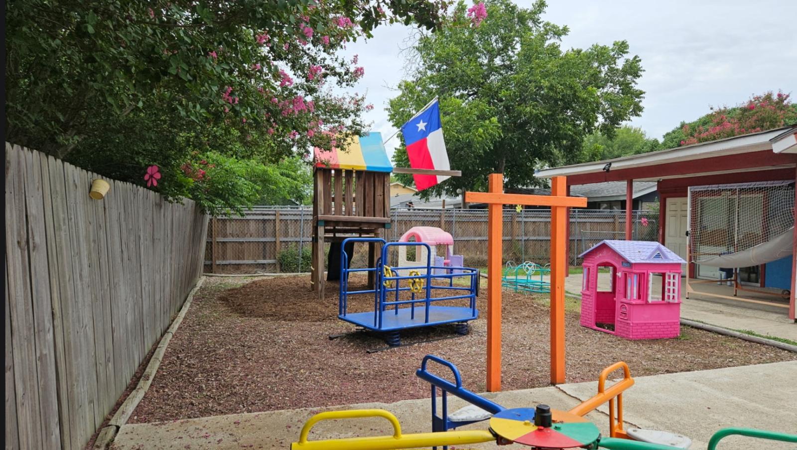 Shaded grass play area with a green shade sail and toddler climbers